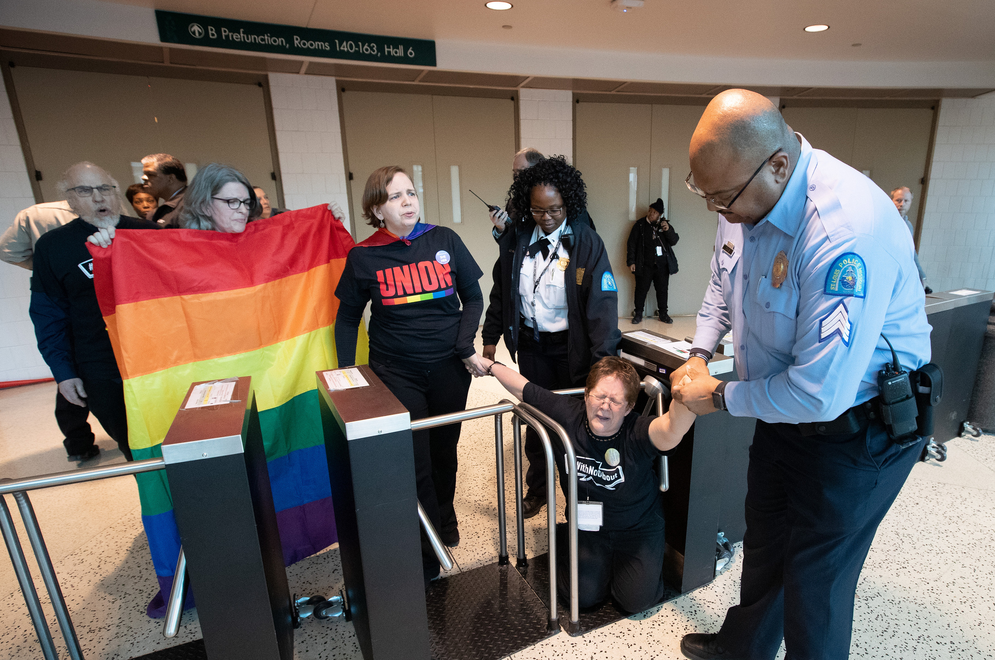 A St. Louis police officer pulls Carol Scott through a turnstile barricade in the Dome at America's Center in St. Louis, site of the 2019 United Methodist General Conference. Scott, a member of the Church of Saint Paul and Saint Andrew in New York, joined other supporters of full inclusion for LGBTQ persons in the life of The United Methodist Church in a protest outside the legislative assembly. Photo by Mike DuBose, UMNS.