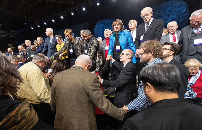 Delegates and bishops join in prayer at the front of the stage before a key vote on church policies about homosexuality during the 2019 United Methodist General Conference in St. Louis. Photo by Mike DuBose, UMNS.