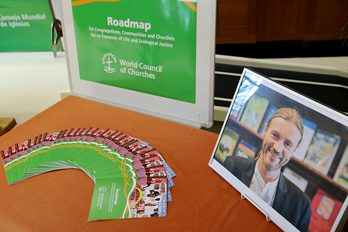 A photo of the late Rev. Norman Tendis stands next to the environmental “roadmap” he created for congregations on behalf of the World Council of Churches. Photo by Ivars Kupcis/WCC.