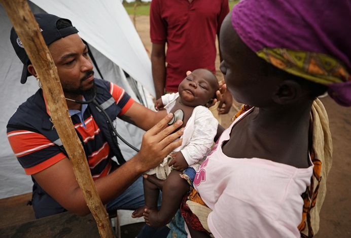A doctor examines a child at a camp for people displaced in flooding in the aftermath of Cyclone Idai, near Beira, Mozambique.  REUTERS/Mike Hutchings, please do not reuse. 