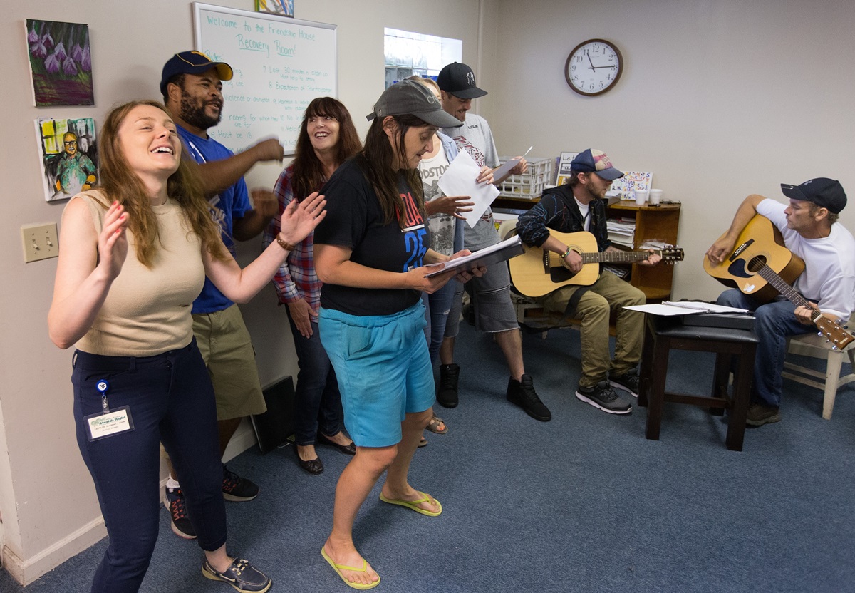 Program director Caitlin Sussman (left) joins in singing with the Voices of Hope choir at Friendship House, a mental health drop-in center in Morgantown, W.Va. 