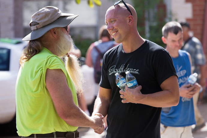 The Rev. Ross Thornton (right) visits with Ronald South while handing out water and praying with clients of the city mission in Huntington, W.Va. Thornton, a 2018 winner of a Denman Award for evangelism, runs a street ministry and pastors Fourth Avenue United Methodist Church in Huntington. Photo by Mike DuBose, UMNS.