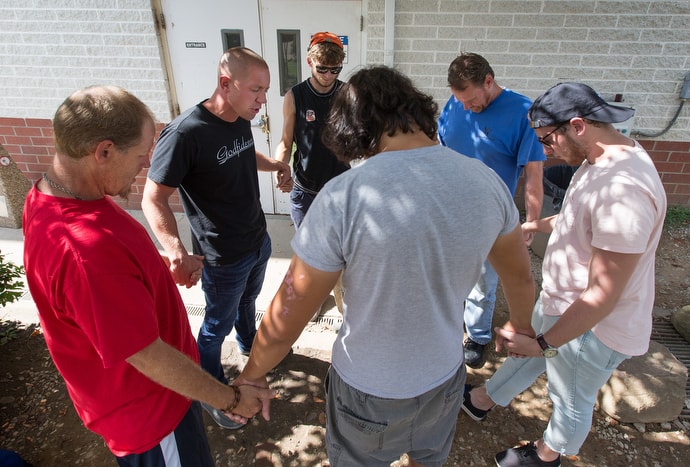 The Rev. Ross Thornton (second from left) and Jasen Thaxton (right) pray with clients of the city mission in Huntington, W.Va. Thaxton is a lay minister and friend of Thornton's. Photo by Mike DuBose, UMNS.