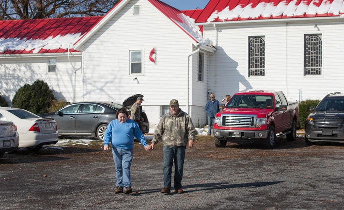 The Revs. Cheryl and Harold George walk out of Oak Grove United Methodist Church in Fisher, W.Va., on their way to deliver meals in the neighborhood. Both are EMTs who have seen the effects of the opioid crisis firsthand. Photo by Mike DuBose, UMNS.