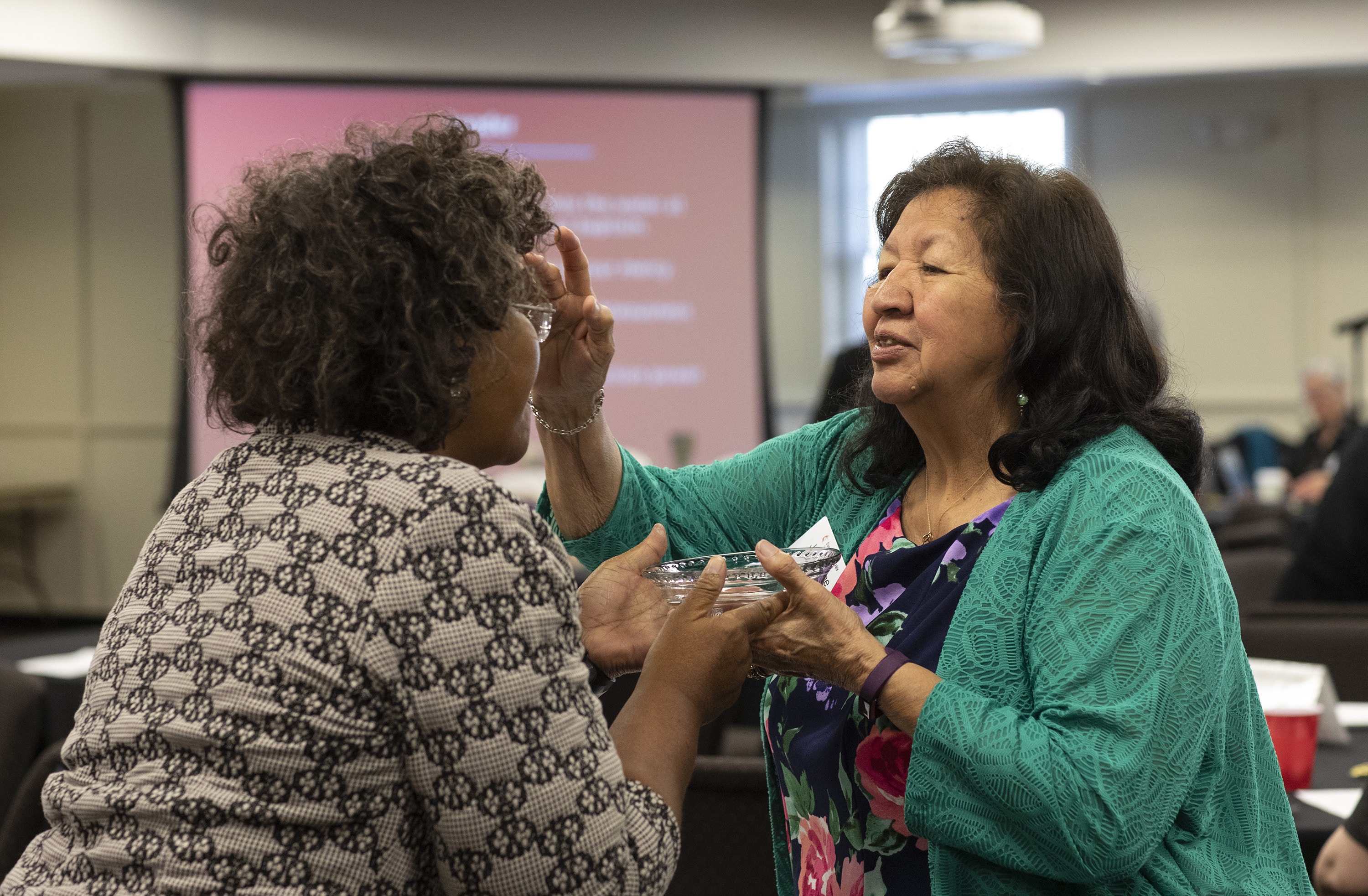 Josephine Deere, right, blesses fellow Connectional Table member Benedita Penicela Nhambiu during a service of baptism remembrance on April 3 at the Connectional Table meeting in Nashville, Tenn. Photo by Kathleen Barry, UMNS.