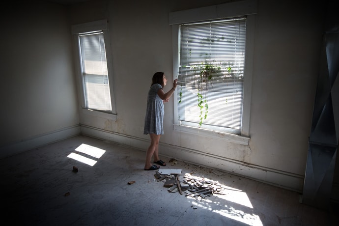 Ann Hammond looks out an overgrown window of a home she hopes to turn into a recovery house for women living with addiction. The house is on the grounds of United Methodist Temple in Clarksburg, W.Va. “Fundraising is slow but we’re getting there, slowly but surely,” she said. Photo by Mike DuBose, UMNS.