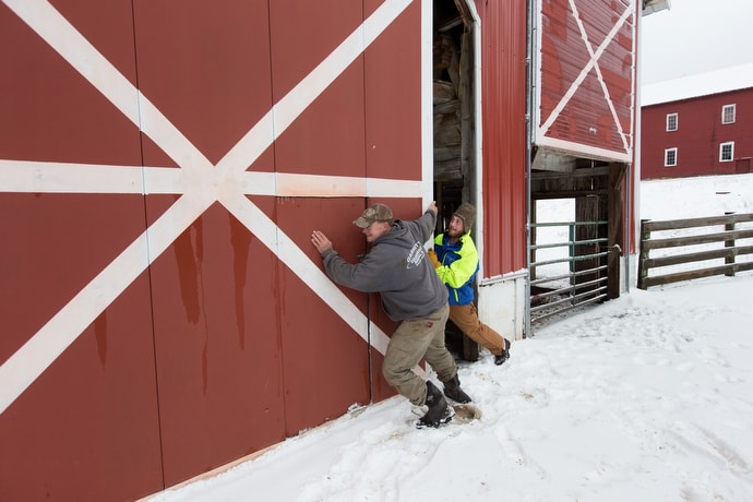 Jim (right), a recovering addict, helps Mark Utterback open an icy barn door at Brookside Farm, part of the Jacob's Ladder rehabilitation program in Aurora, W.Va. Utterback is director of farming for the program. Photo by Mike DuBose, UMNS.