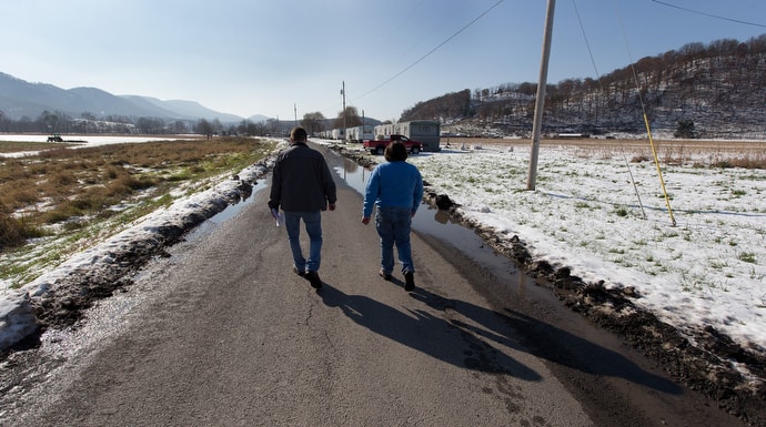 Wayne Worth (left) and the Rev. Cheryl George walk through a trailer park in Fisher, W.Va., while handing out resource information for those struggling with addiction.