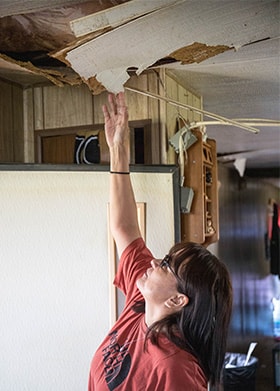 Susan Shangreaux, a resident on the Pine Ridge Indian Reservation, points to a spot on her ceiling that caved in from heavy snow after severe winter storms. Photo by Ginny Underwood, UM News. 