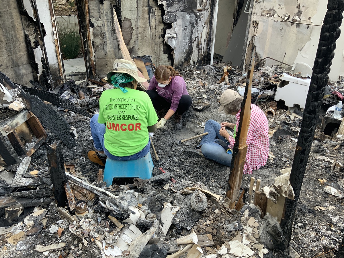 From left, United Methodist Committee on Relief volunteer Helen Quirocho, Magnolia Becker and UMCOR’s Judy Lewis sift through wildfire wreckage in what is left of Becker’s home in the Truncas canyon of Malibu, California, on April 6, 2019. Photo by Doug Lewis.
