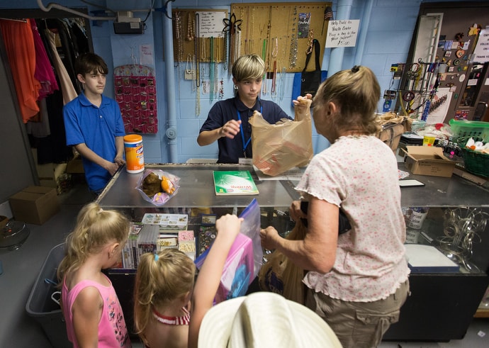 opioids-ministry-with-children-8-thrift-store Cameron (center) bags purchases for a family in the thrift store at House of the Carpenter in Wheeling, W.Va. Photo by Mike DuBose, UM News.