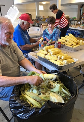 Volunteers shuck corn at Clarksville United Methodist Church, which has provided meals to those affected by flooding or working to fortify the town against an overflowing Mississippi River. From left are Bill Blakey, Bob Frank, Linda Frank and Jo Anne Smiley, Clarksville’s mayor. Photo by Janie Busch.