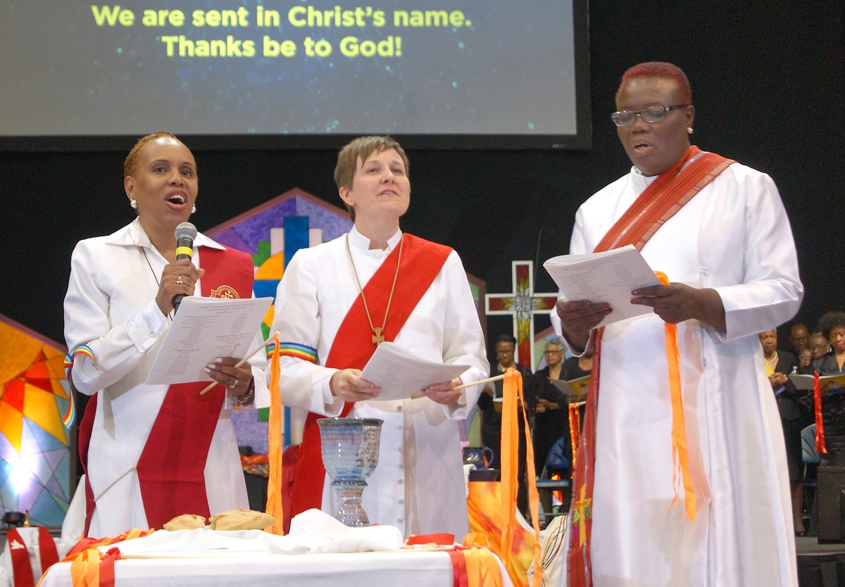 Newly ordained deacons lead the benediction at the end of the ordination service during the New York Annual Conference meeting at Hofstra University in Hempstead, N.Y. From left are the Revs. Arletha (Lisa) Miles Boyce, Lea A. Matthews and Janet L. Cox. Matthews says she sees her ministry as a helping hand to marginalized people in the world, including LGBTQ people like herself and her wife. Photo by Stephanie Parsons, NYAC.
