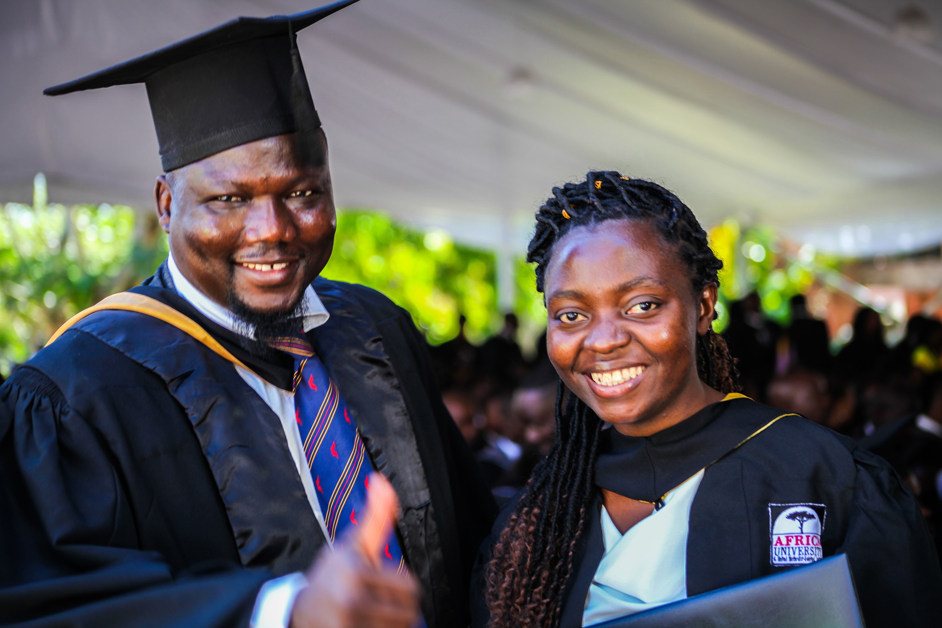 클로딘 미기샤 (우측)가 짐바브웨이 무타레에 위치한 아프리카대학교를 졸업하면서, 웨남 다발레씨로부터 축하를 받고 있다. 콩고의 고마 출신인 미기샤는 아프리카대학교 개교 25주년을 맞는 2019년의 졸업생 중 한 명이다. 다발레씨는 이 학교의 국제학생처장이다. 사진 제공, 아프리카대학교.