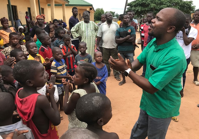 The Rev. Ande Emmanuel leads children in singing a church song at a camp for internally displaced persons in Jalingo, in northern Nigeria. The camp is one of 10 in Jalingo where The United Methodist Church provides ministerial support and supplies. Photo by Tim Tanton, UM News.