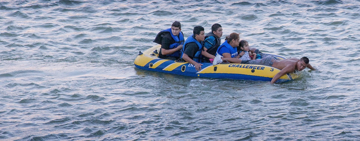 A coyote, or smuggler, (right) uses his hands to paddle a rubber raft full of immigrants across the Rio Grande from Mexico to the U.S. side of the river in Roma, Texas, in August 2014. Recent reports of the suffering of children at immigrant detention centers and immigrants drowning calls for reform, say many United Methodist leaders. File photo by Mike DuBose, UM News.