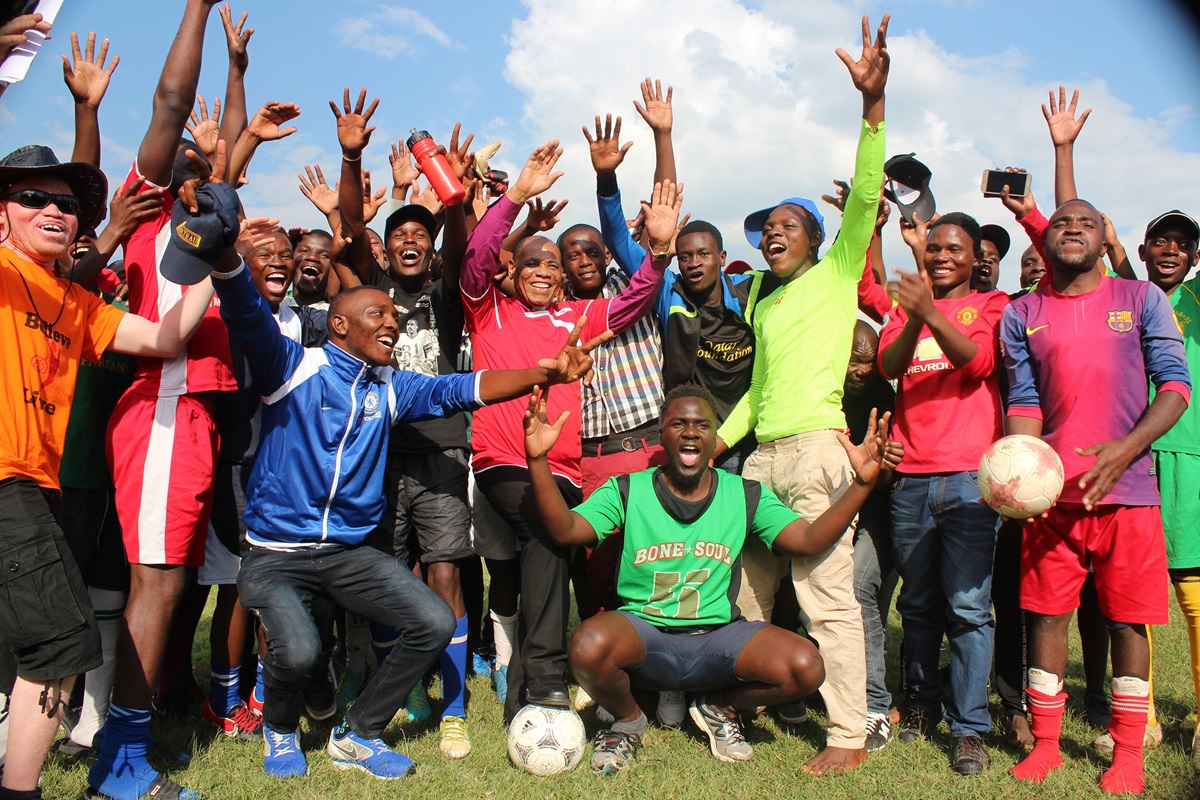 Bishop Eben K. Nhiwatiwa (center, with foot on ball) celebrates with youth teams after playing an exhibition soccer game together at Avonlea Primary School in Harare, Zimbabwe. The Zimbabwe Episcopal Area has put a focus on sports and fitness as a way to get members healthy and bring new souls to Christ. Photo by Kudzai Chingwe, UM News.