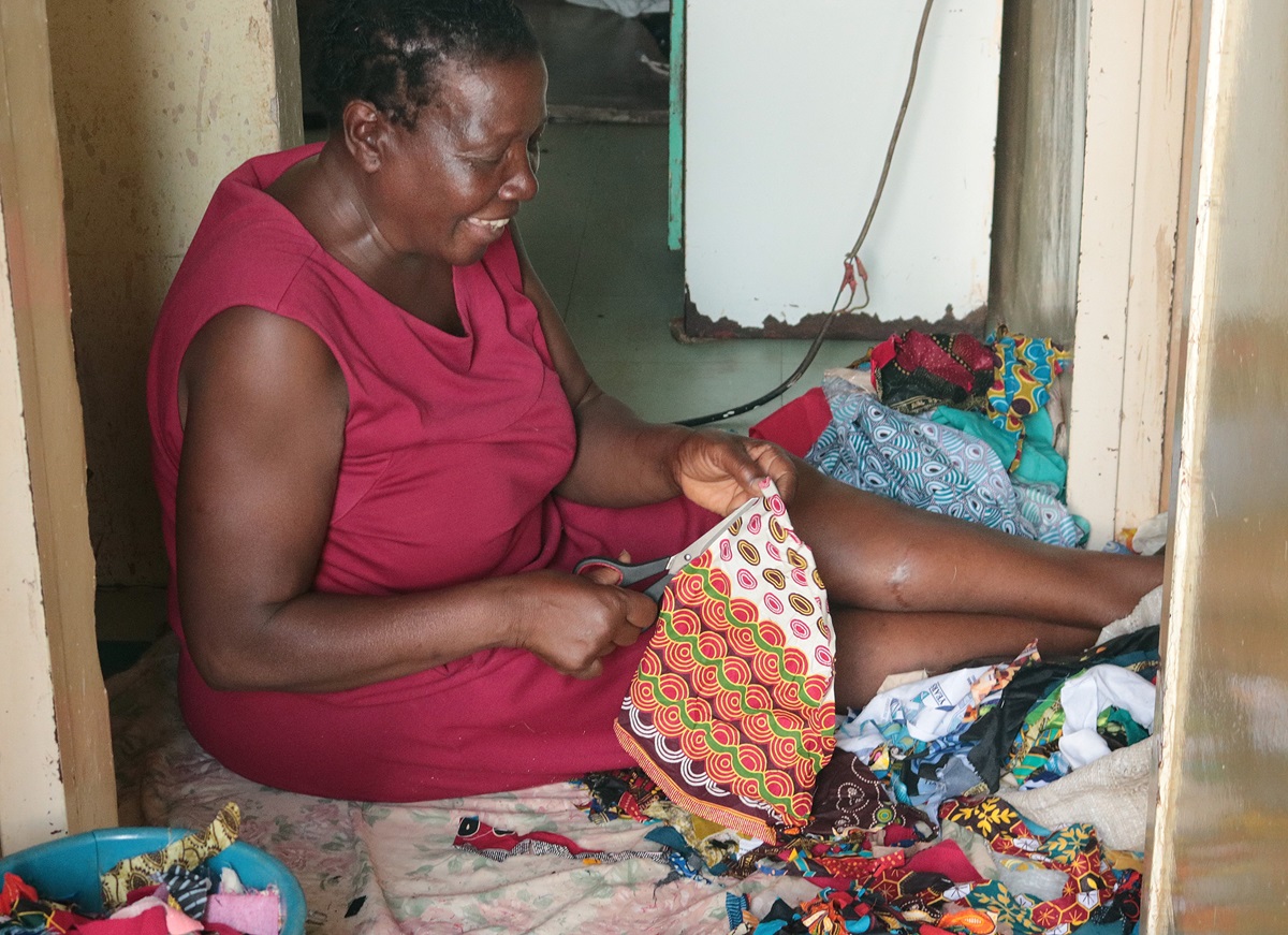 Tapiwa Nyawasha cuts strips from scrap pieces of plastic that she will use to make bed, bath and door mats as a way to increase income and empower widows and single mothers. Tapiwa  is a member of Kuwadzana Extension United Methodist Church in Harare, Zimbabwe. Photo by Chenayi Kumuterera, UM News.