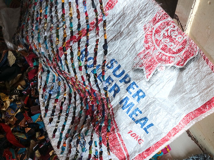 Tapiwa Nyawasha weaves strips of salvaged plastic into household mats. Photo by Chenayi Kumuterera, UM News.