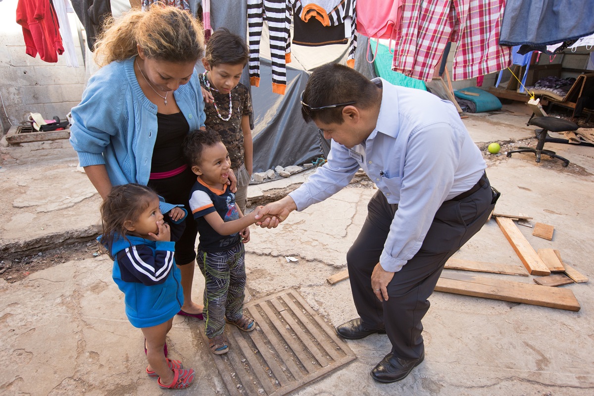 The Rev. Joel Hortiales, a United Methodist missionary with the Board of Global Ministries, visits with Lizbeth and her three children, Bridgette, 3, Caleb, 4, and Alvaro Jose, 10, at the Hosanna Refugio Para Mujeres, in Mexicali, Mexico, in December 2018. The family was part of a migrant caravan from Central America. The United Methodist Immigration Task Force is urging support for migrants living in sanctuary churches who have been fined by the federal government. File photo by Mike DuBose, UM News.