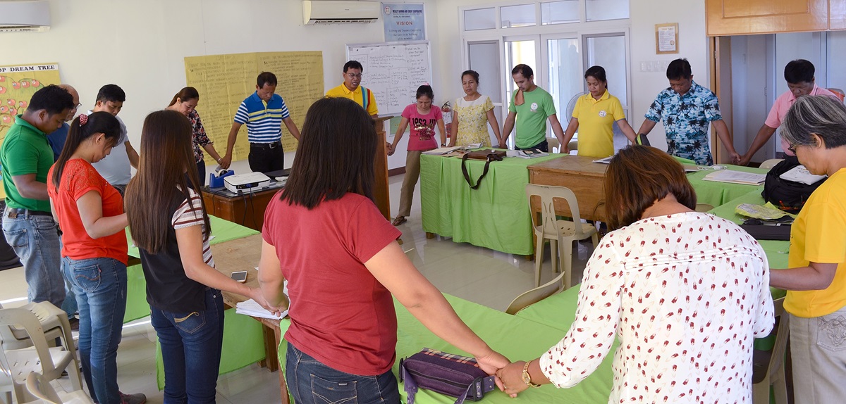 Staff members and management of the Wesley Savings and Multipurpose Cooperative hold hands in prayer during a meeting at their office in San Isidro, Philippines. The cooperative’s purpose is “to alleviate poverty and enhance the dignity and quality of life of people,” said the Rev. Ferdinand J. Valdez, top executive of the cooperative. Photo courtesy of the Rev. Ferdinand J. Valdez.