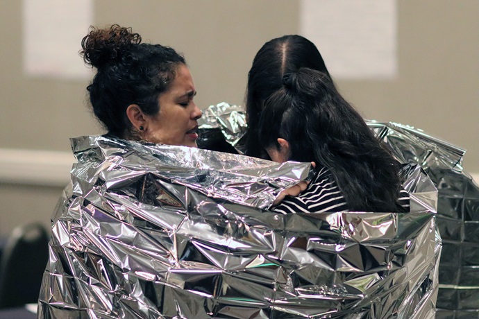 La Pastora Dorlimar Lebrón orando con dos jóvenes, envueltas en lel mismo tipo de mantas que cobijan a los/as niños/as y adultos/as inmigrantes que se mantienen detenidos, y algunos de ellos hacinados, en los centro de detención que ICE mantiene en la frontera. Foto por Michelle Maldonado, UMCOM.