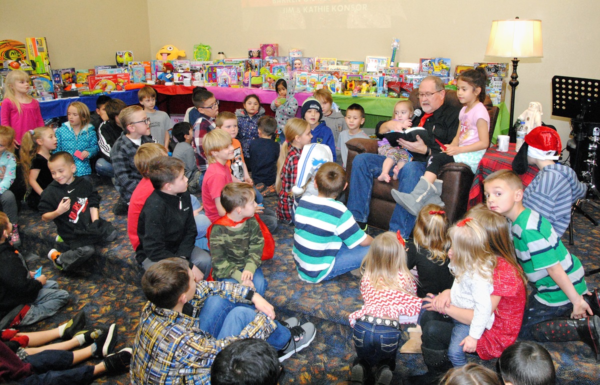 The Rev. James Konsor reads to children during a Christmas season event at the Bakken Oil Rush Ministry in Watford City, N.D. The ministry provides clothing, household items, furniture and more to needy families at a nominal price. Photo courtesy the Bakken Oil Rush Ministry.