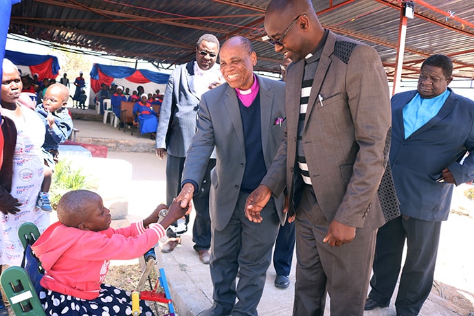 Portia Kasuso shakes hands with Bishop Eben K. Nhiwatiwa during a United Methodist revival service in Murewa. The young girl was a guest of honor at the service. “Having Portia at this revival is evidence of how much the church can become a home for all people in spite of their conditions,” Nhiwatiwa said. Photo by the Rev. Taurai Emmanuel Maforo, UM News.