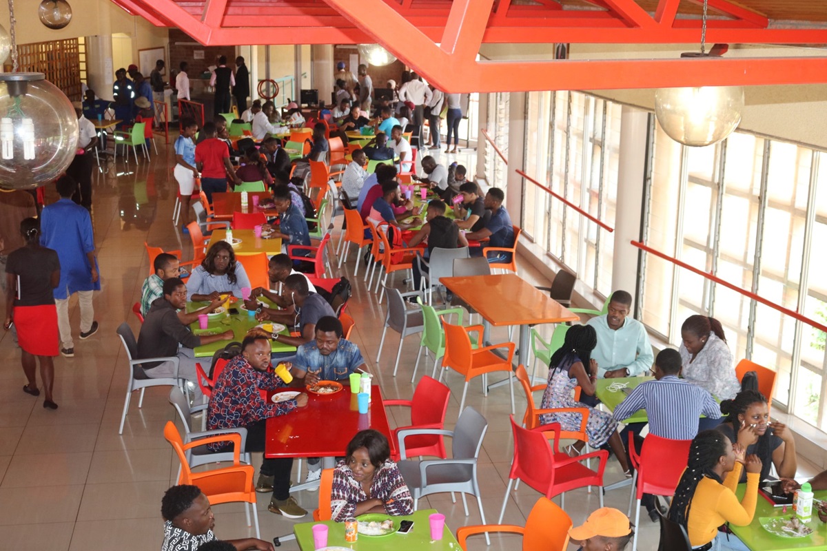 Los/as estudiantes comen en la cafetería de la Universidad de África, que sirve a unas 1.200 personas durante el almuerzo y la cena. Para manejarse en tiempos económicos difíciles, el departamento de servicios de alimentos ha estado suministrando alimentos y administrando porciones. Foto por Eveline Chikwanah, Noticias MU.