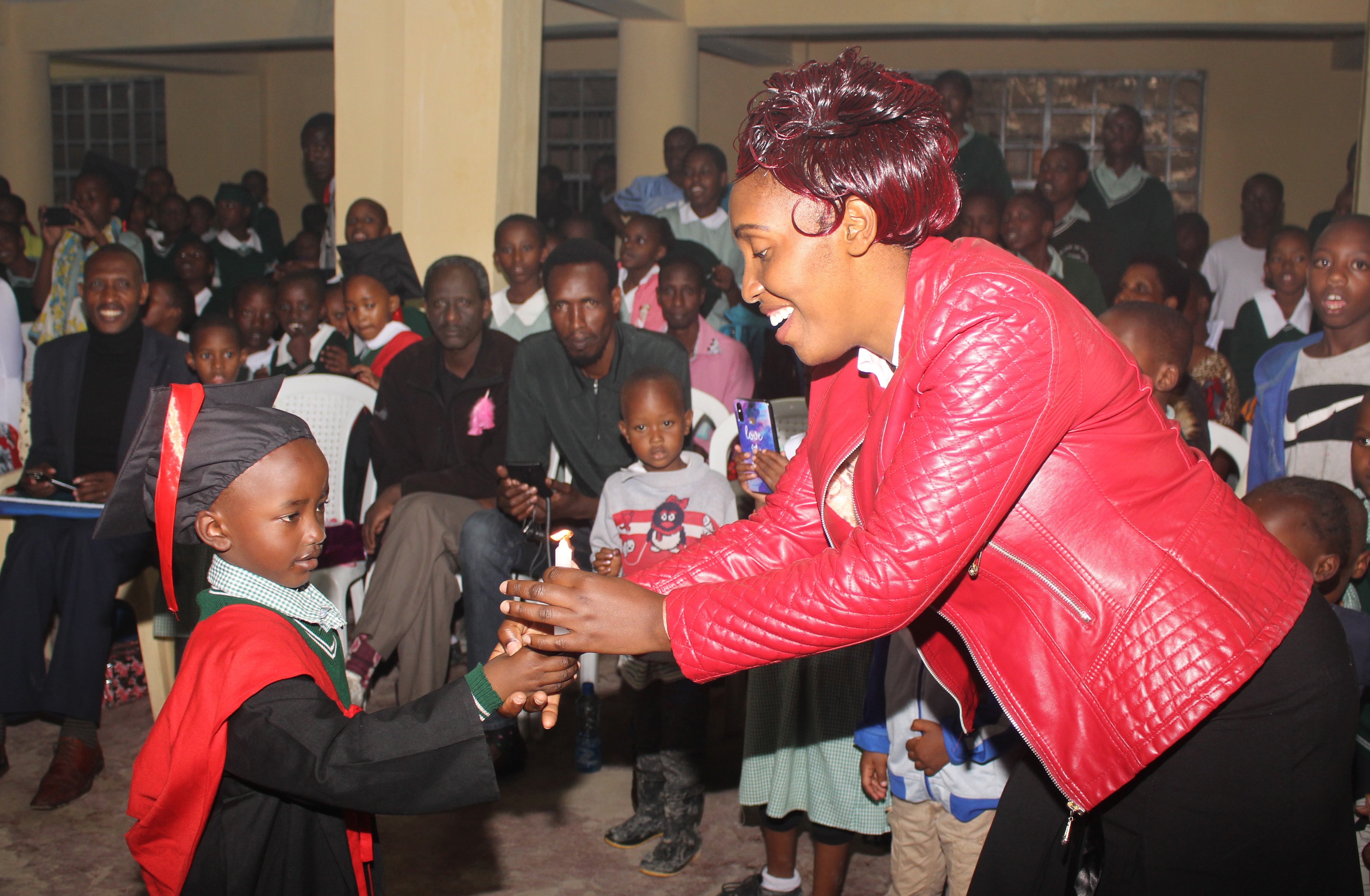 A Congolese student passes on a candle to his teacher as a symbol of successfully completing the Early Years of Education course at Dr. B.T. Cooper United Methodist School in Nairobi, Kenya. Of the 310 students enrolled at the school, 200 are Congolese children with refugee status. Photo by Gad Maiga, UM News.