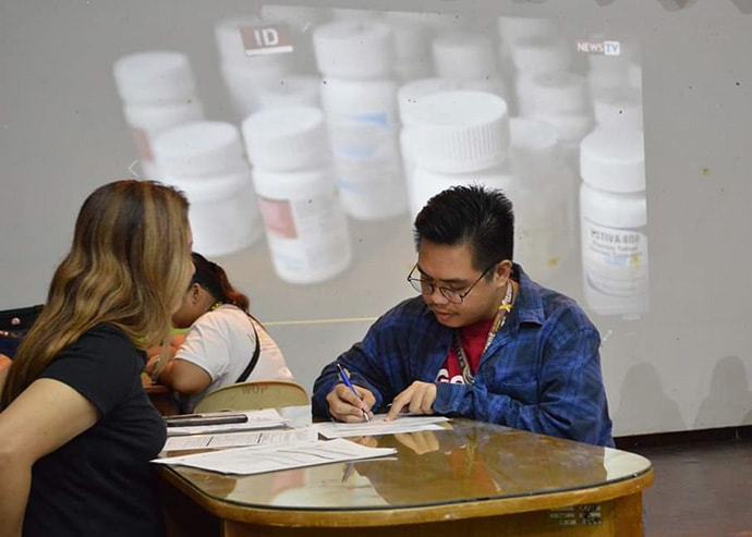 John Mark Santiago, former student governor of the College of Education local council at Wesleyan University-Philippines, signs paperwork to have his blood tested at an HIV and AIDS education and prevention forum at the university in Cabanatuan City, Philippines, on Oct. 30. Photo by Jon Balagan