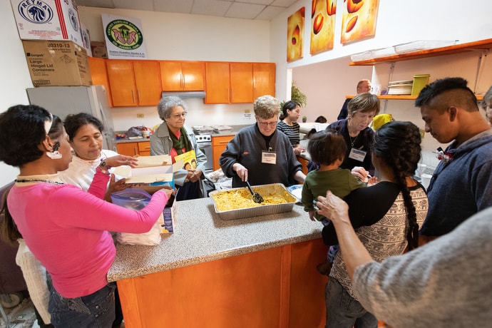 Volunteers from El Calvario United Methodist Church in Las Cruces, N.M., serve a meal for migrants at an immigrant processing center in Juárez, Mexico, at the foot of the Paso del Norte border crossing into El Paso, Texas. Volunteers from Mexico and the U.S. serve regular meals and offer educational programming for children while families wait to make asylum claims in the U.S. Photo by Mike DuBose, UM News.