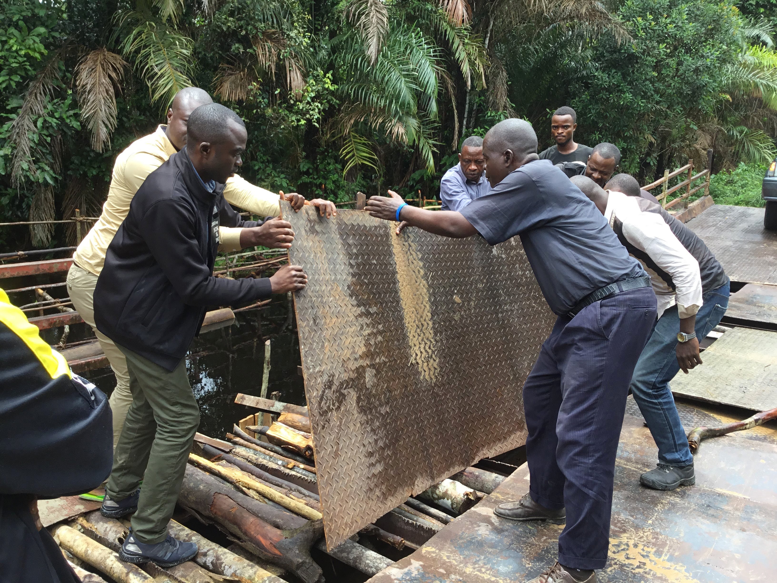 Men lay a metal sheet over a broken bridge so that Bishop Gabriel Yemba Unda and his delegation can continue their travels to some of the most remote areas in the East Congo Conference. Photo by Judith Osongo Yanga, UM News.