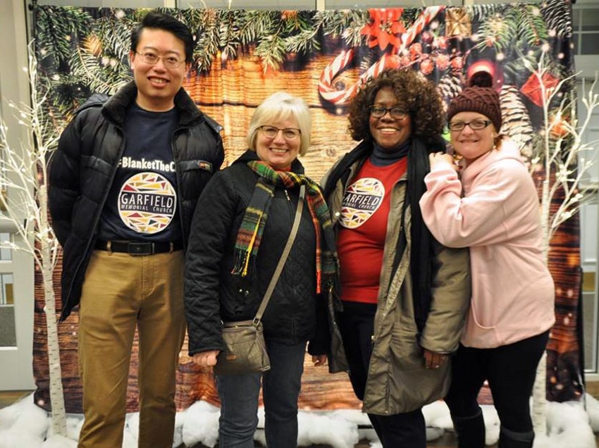 Garfield Memorial Church near Cleveland, Ohio, finds various ways to be make people feel welcome, including having a backdrop where people can take Christmas photos. From left are David Chung, Cheri Shumaker, Johnnie Hilliard and Nikki Froehlich. Photo courtesy of Garfield Memorial Church. 