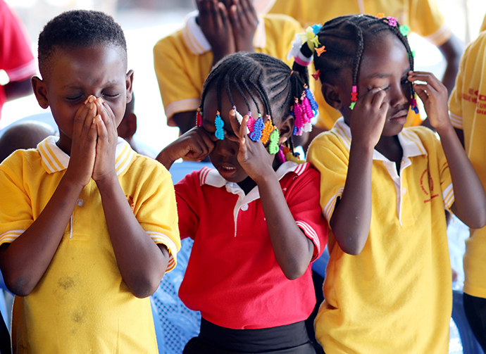 (A partir de la gauche) Eunice Mel, 9 ans, Syntiche Tia, 5 ans, et Gnonsio Tryphene, 9 ans, membres de l'église Méthodiste Unie Bethel du camp de réfugiés Ivoriens d'Ampain (Ghana) prient durant une célébration d’arbre de Noël organisé dans le camp. Le district d'Aboisso de l'Église Méthodiste Uie de Côte d'Ivoire soutient cette communauté. Photo de Isaac Broune, UM News.