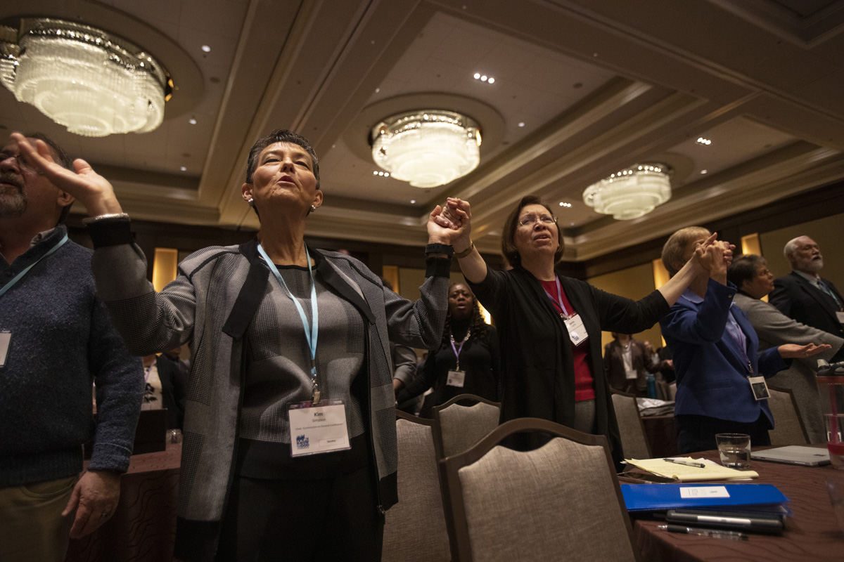 Kim Simpson, chair, Commission on General Conference, and Janice Griffith, Illinois Great Rivers, join hands in prayer during opening worship at the 2020 United Methodist Pre-General Conference held in Nashville, Tenn. Photo by Kathleen Barry, UM News.