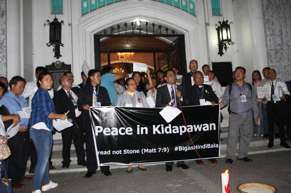Bishop Rodolfo A. Juan (center) and the Rev. Rubynell Estrella lead a candlelight prayer service at United Methodist Church in Manila for Lumad farmers caught in a violent protest at the Spottswood United Methodist Church in April 2016. United Methodist leaders have condemned a recent raid on a mission center that houses 500 displaced Lumad in Mindanao, Philippines. File photo courtesy of Gladys P. Mangiduyos, UM News.
