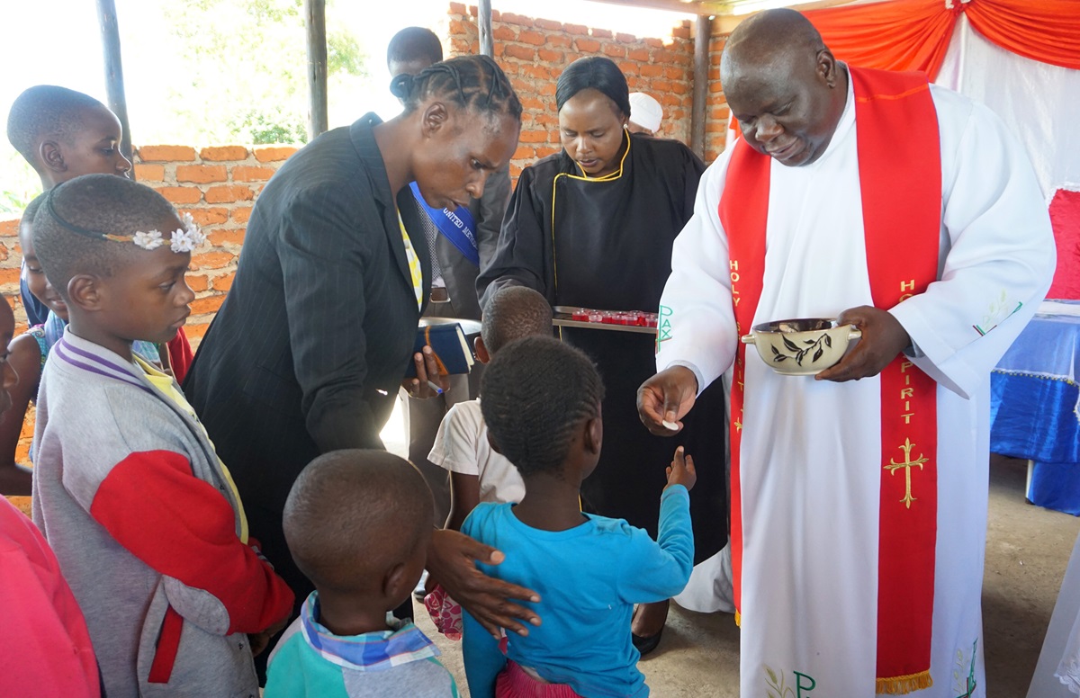 The Rev. Oscar Nyasha Mukahanana, Harare East District superintendent, distributes Holy Communion to children and others at Maximum Salvation United Methodist Church in Manresa, Zimbabwe. The church, near Chikurubi Maximum Security Prison, serves inmates, officers and their families. Photo by Kudzai Chingwe, UM News. 