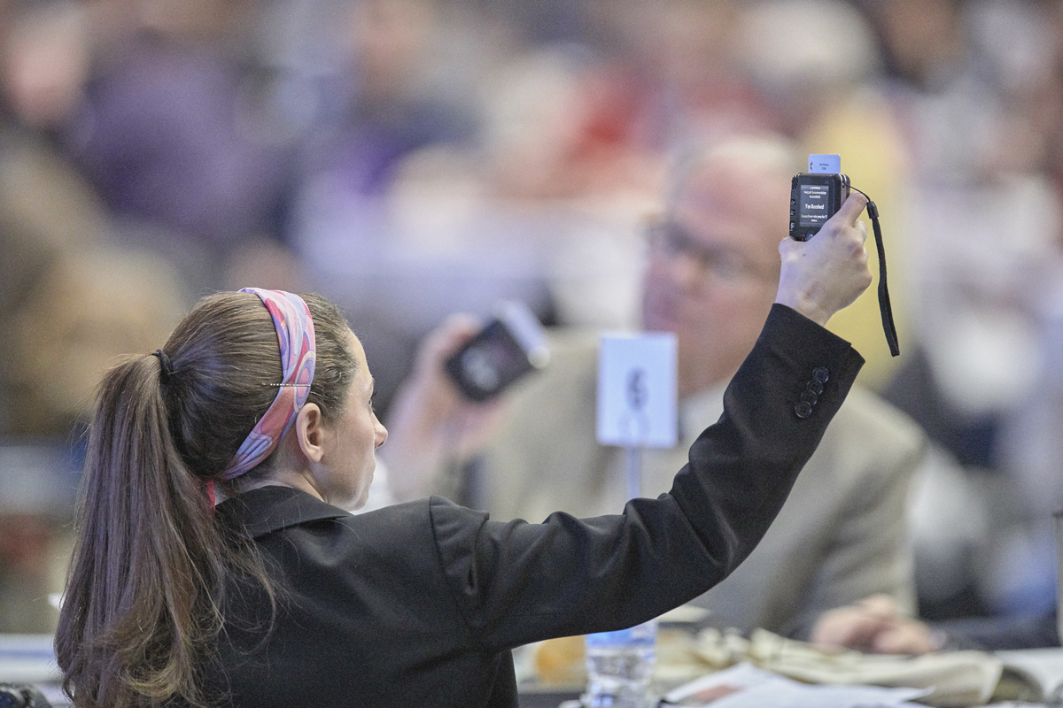 A delegate holds her voting device aloft as she contemplates a Feb. 26, 2019, vote during the special General Conference in St. Louis. General Conference organizers have named a think tank to consider how best to process legislation at the 2020 General Conference. Photo by Paul Jeffrey, UM News.