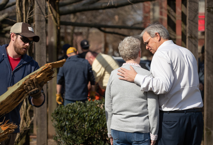 Bishop William McAlilly (right) comforts the Rev. Judi Hoffman in the park outside East End United Methodist Church in Nashville, Tenn., while volunteers clean up debris from a March 3 tornado that heavily damaged the church's sanctuary and offices. Photo by Mike DuBose, UM News.