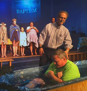 A man is baptized at Aloma United Methodist Church in Winter Park, Fla. The parish has closed its church building and is holding Sunday services in a local bar. Video image courtesy of Aloma United Methodist Church.   