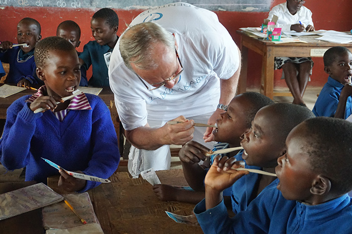 Dr. Kjell Gustafsson, a dentist from Sweden, helps children clean their teeth at Mutambara Central Primary School in Chimanimani, Zimbabwe. A Swedish dentists and hygienists visits rural Zimbabwe twice a year to provided free services to children, including oral health education, screenings, fillings and extractions of broken and decayed teeth. Photo by Kudzai Chingwe, UM News.