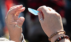 Cheryl Stone holds a shard of glass from a stained glass window that was destroyed by a tornado at East End United Methodist Church in Nashville, Tenn. Church families were offered the glass pieces during an outdoor worship service in the park adjacent to the church. Photo by Mike DuBose, UM News.
