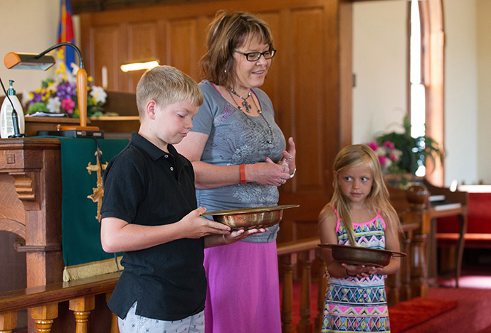 Pastor Laura Vincent (center) prays with collectors Zane Barnt (left) and Adison Embrey before they receive the offering at Shiloh United Methodist Church near Clinton, Ky. A 2015 file photo by Mike DuBose, UM News.