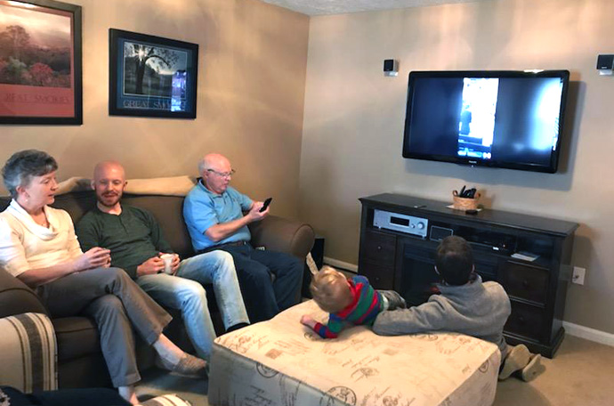 Members of the Williams family gather at the home of David (right on couch in blue shirt) and Susan Williams (left on couch in white shirt), to watch a livestream of the 11:15 a.m. service of Christ Church United Methodist Church in Louisville, Ky. Seated on the floor to far right is their son, Ben Williams, a musician at the church. Photo by Lesley Williams, courtesy of the Kentucky Conference.