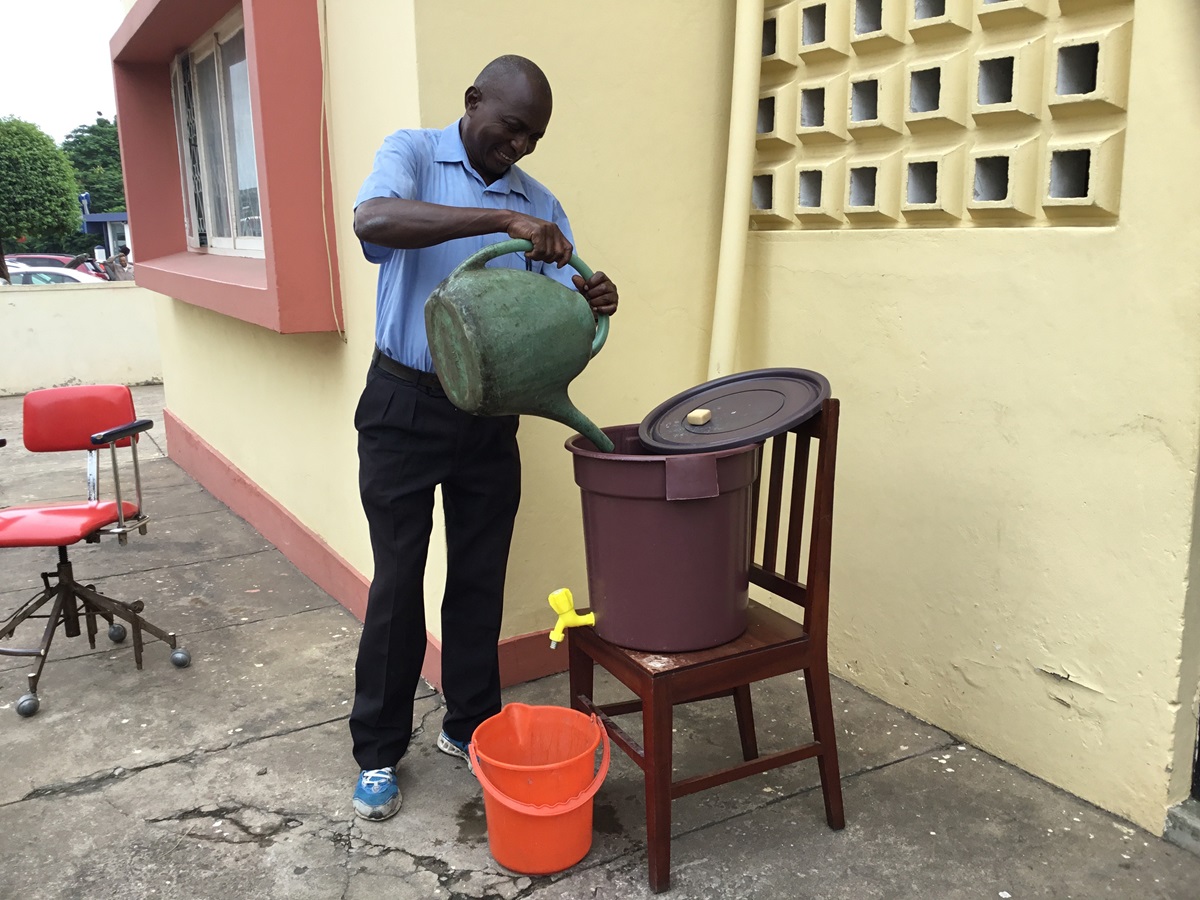 Senhor Alfredo Rafael Chume, um dos funcionários da Igreja que guarnece os Escritórios, adiciona água com produtos químicos a entradas dos Escritórios Centrais. Foto de João Filimone Sambo.