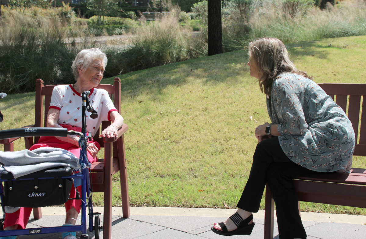 The Rev. Kellie Sanford (right) practices social distancing while visiting with a resident of the CC Young Senior Living community in Dallas. Sanford, a licensed local pastor in The United Methodist Church, serves as chaplain for the facility. Photo by Jennifer Griffin.