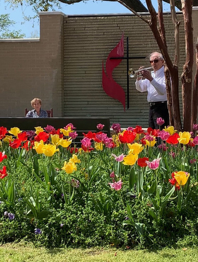 John Gould plays a hymn on his trumpet for Joan Jackson in the courtyard of the CC Young Senior Living community in Dallas after Jackson’s husband Robert passed away Sunday, March 22, 2020. When social distancing prevented a typical memorial service, Gould offered to play a few hymns outside in the common area. Photo from video by Eric Markinson.