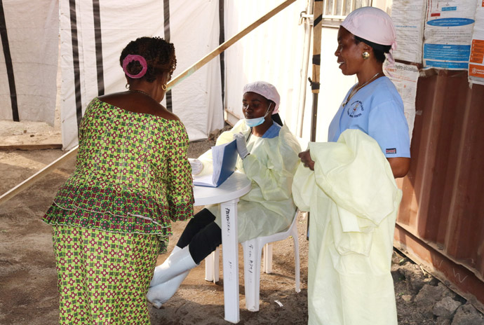L'infirmière Anny Butunga (assise) prend des informations sur un patient dans une chambre d'isolement d’Ebola à l'hôpital Méthodiste Uni Irambo à Bukavu, RD Congo, sous le regard d'une autre infirmière. Toutes les chambres d'isolement d’Ebola des hôpitaux Méthodistes Unis de la région sont en train d'être transformées en centres d'isolement du COVID-19. Photo de Philippe Kituka Lolonga, UM News.