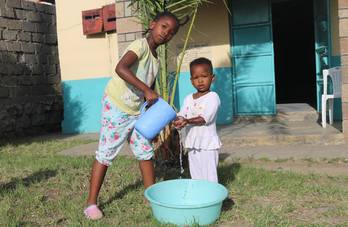 Shantel Resse, neuf ans, lave les mains de sa petite sœur, Reina Muthoni, à l'église Méthodiste Unie Kayole St. John's de Nairobi, au Kenya. Les églises du Kenya exhortent leurs membres à se laver les mains avec du savon ou du désinfectant pour mains afin d'arrêter la propagation du coronavirus. Photo de Gad Maiga, UM News.